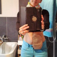 Foto: junge Frau mit Beutel am Bauch macht ein Selfie