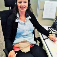 Foto: junge Stomaträgerin arbeitet im Büro und zeigt ihren Versorgungs-Beutel