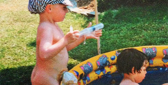 Foto: Kind mit Beutel am Bauch spielt im Sommer im Garten